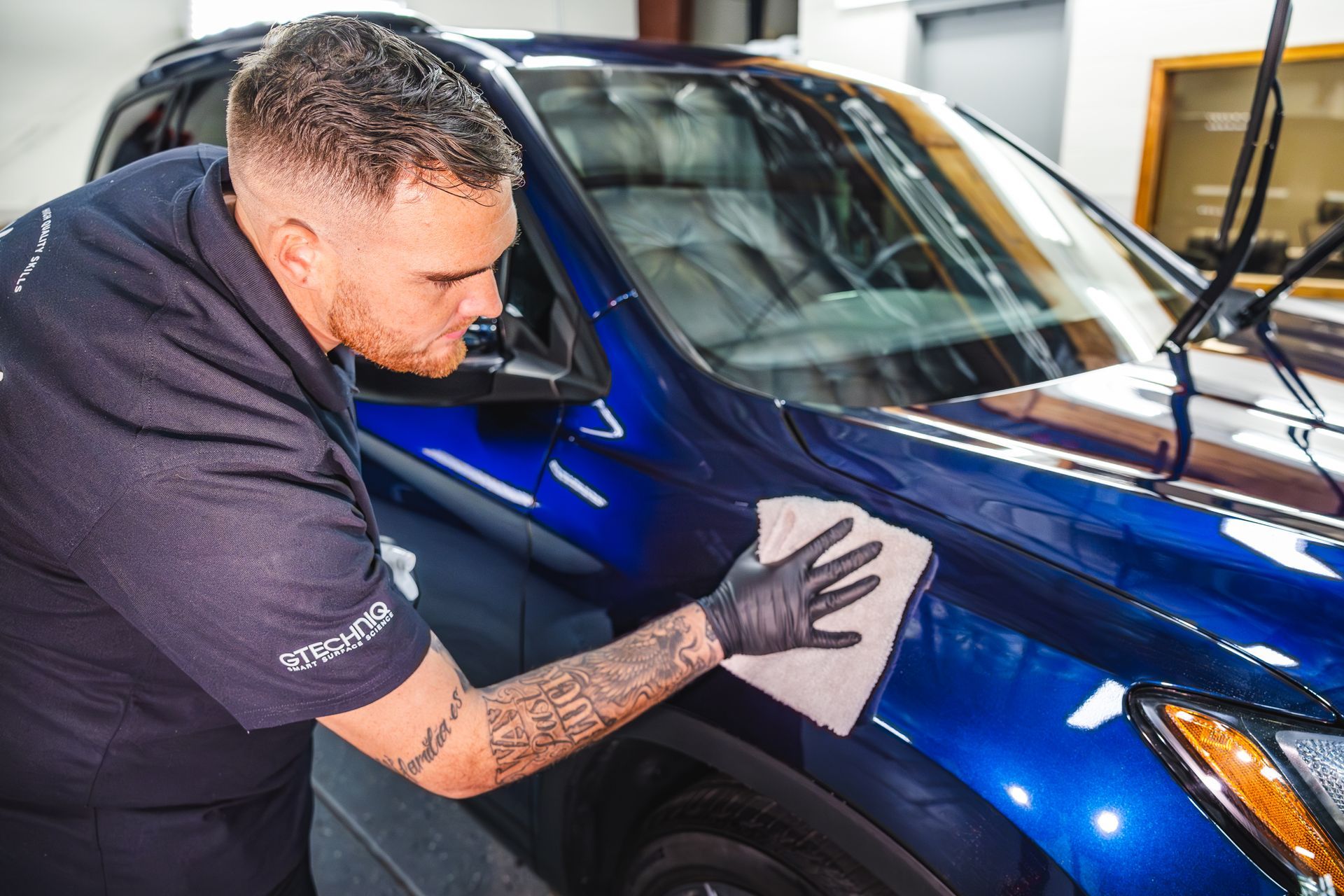 A person is washing a car with foam and a cloth.