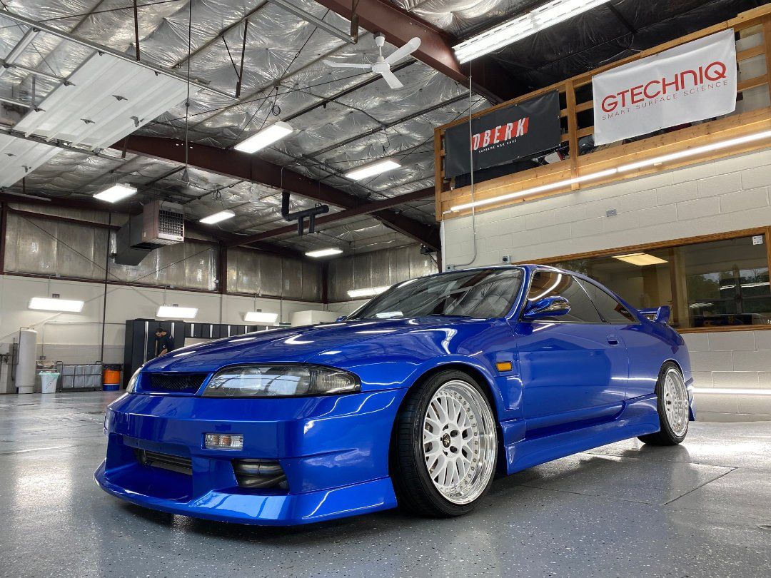 A blue car is parked in a garage next to a sign that says gtechniq.