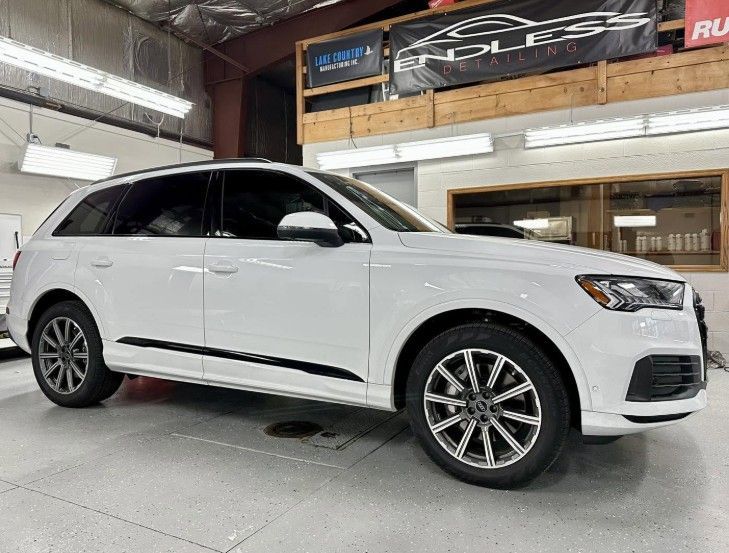 White Audi SUV parked indoors at a dealership, side view