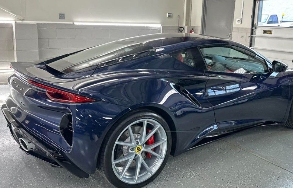 Dark blue sports car in a garage, rear three-quarter view with silver wheels and red brake calipers