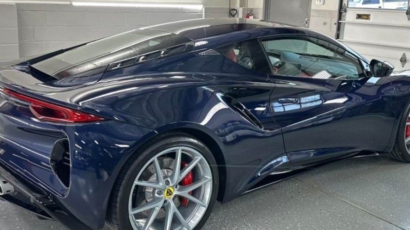 Blue sports car with silver wheels and red brake calipers parked indoors.