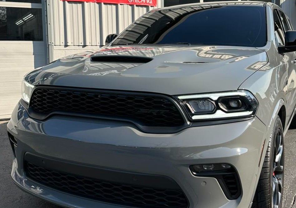 Gray Dodge Durango SUV with black grille and hood scoop parked near a building.
