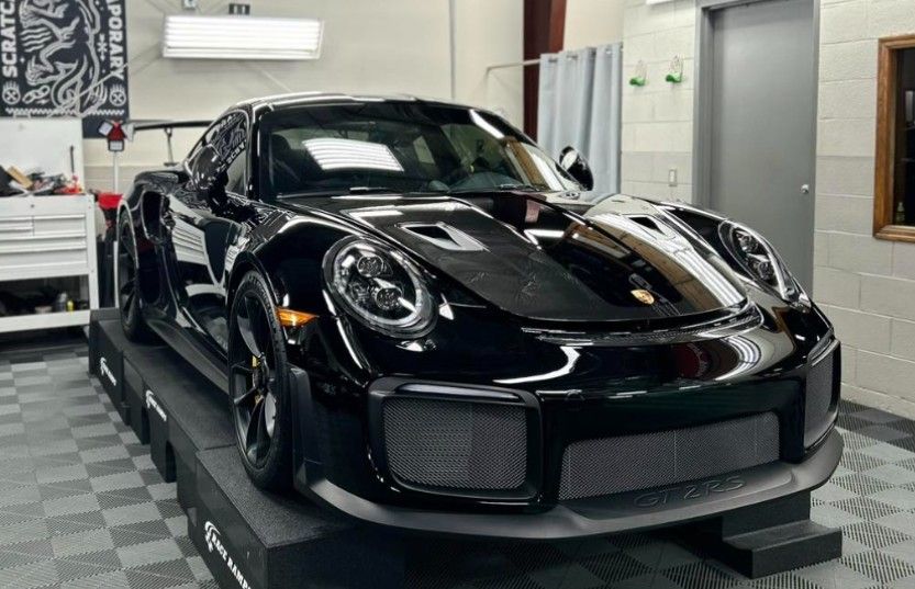 Black Porsche sports car displayed indoors on a platform in a garage