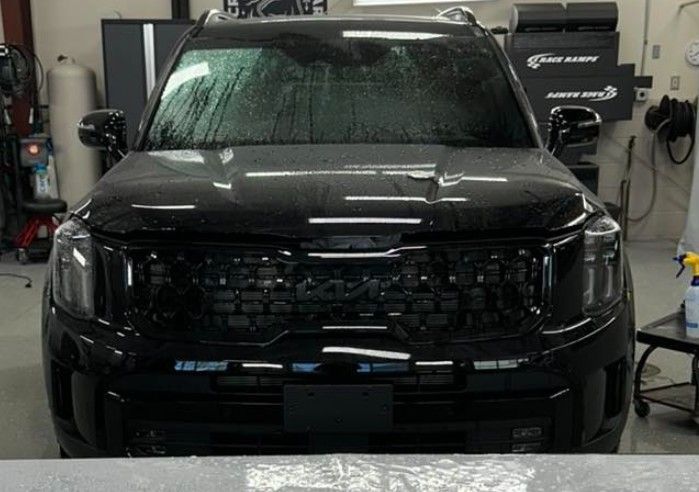 Black SUV in a garage, windshield covered in water, front view.