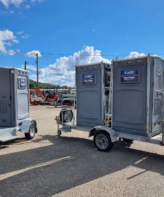 Portable restrooms on trailers in a parking lot under a blue sky