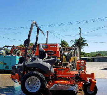 Orange and black utility equipment mounted on a trailer in a sunny parking lot