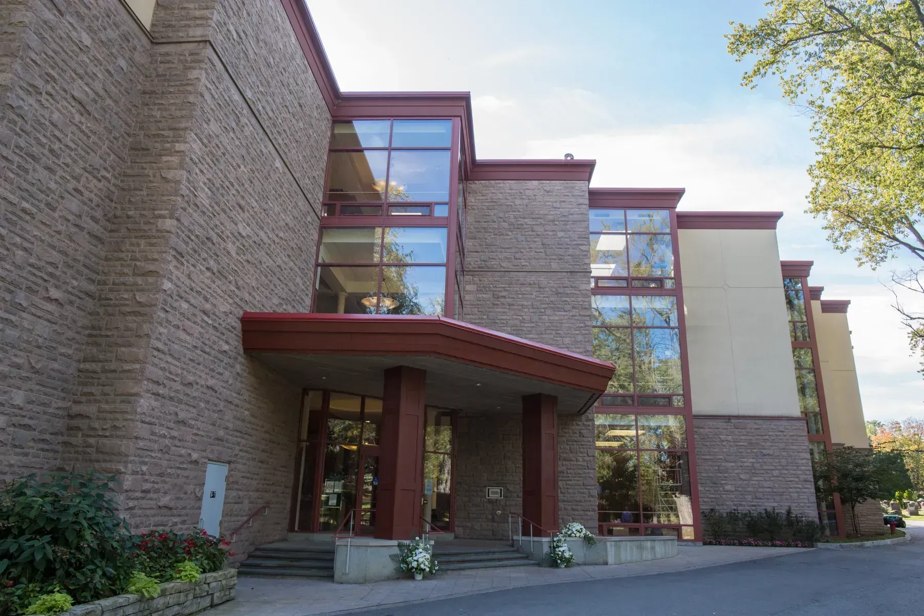 Modern brick building entrance with tall glass windows and a red awning.