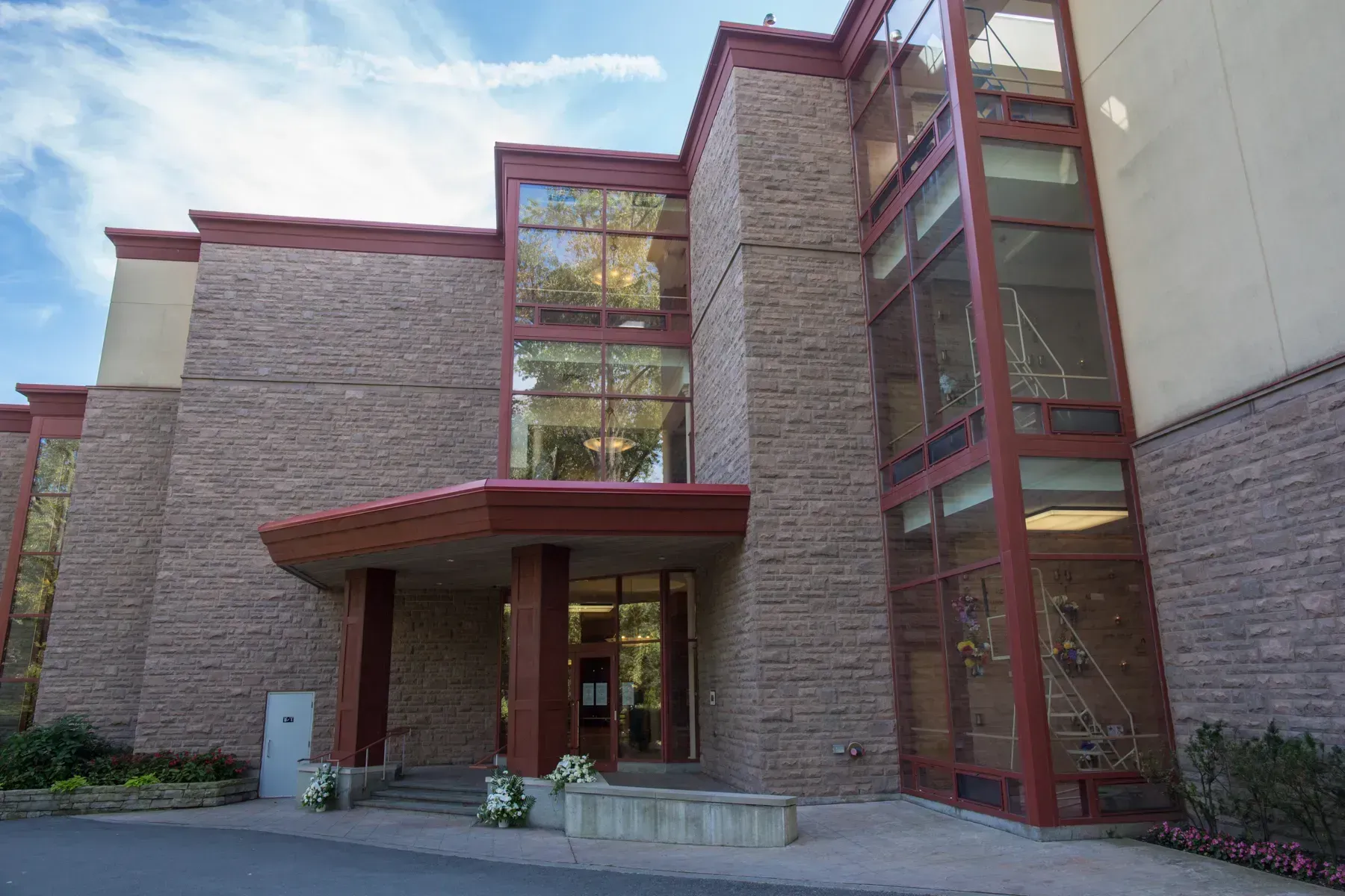 Modern brick building entrance with red-framed windows and covered walkway