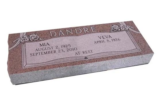 Pink granite gravestone with engraved plaque and floral corners, shown at an angle.