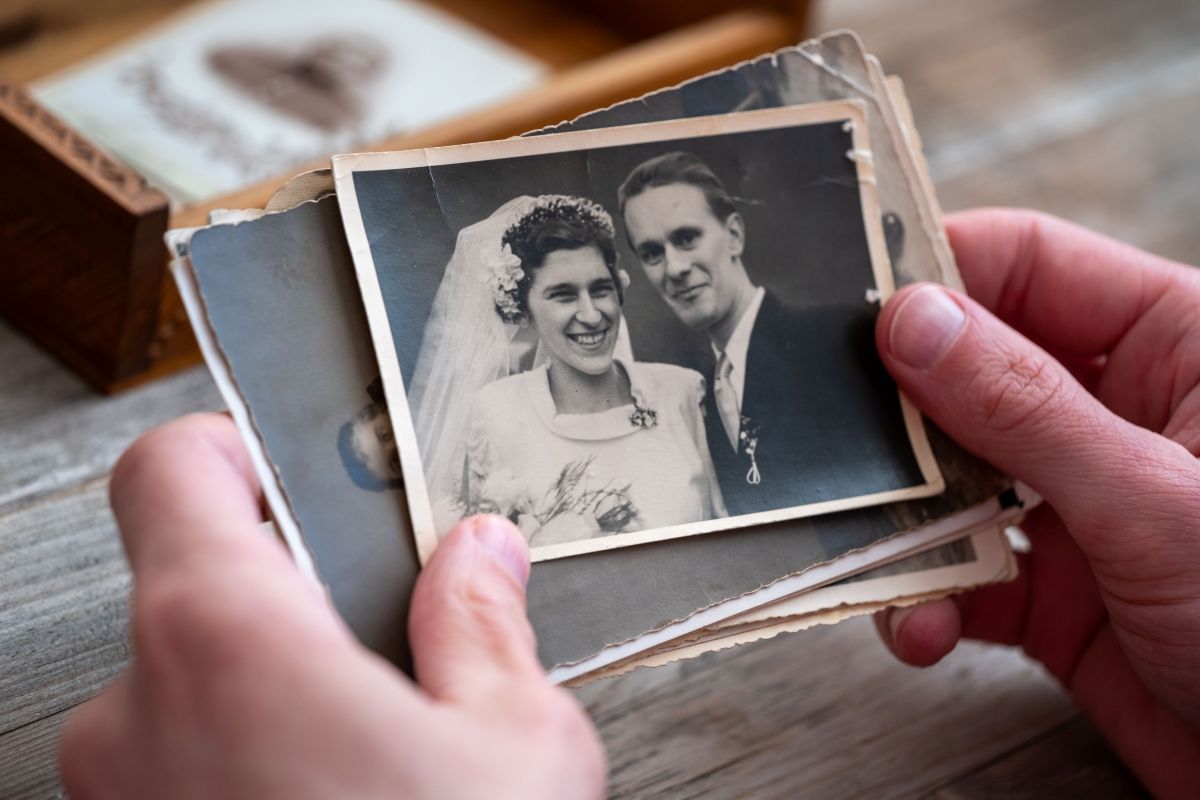 Hands holding an old black-and-white wedding photo from a box of vintage photographs