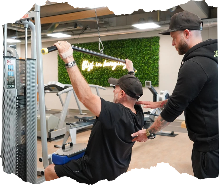 Een man die een lat pulldown-machine gebruikt als trainingshulpmiddel, begeleidt hem in een sportschool.