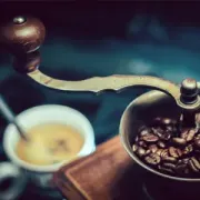 Vintage coffee grinder with roasted beans and a cup of espresso nearby