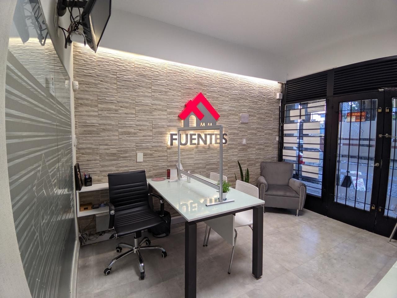 Vestíbulo de oficina moderno con escritorio, sillas, pared de piedra y puertas de cristal bajo el logotipo de FUENTES.
