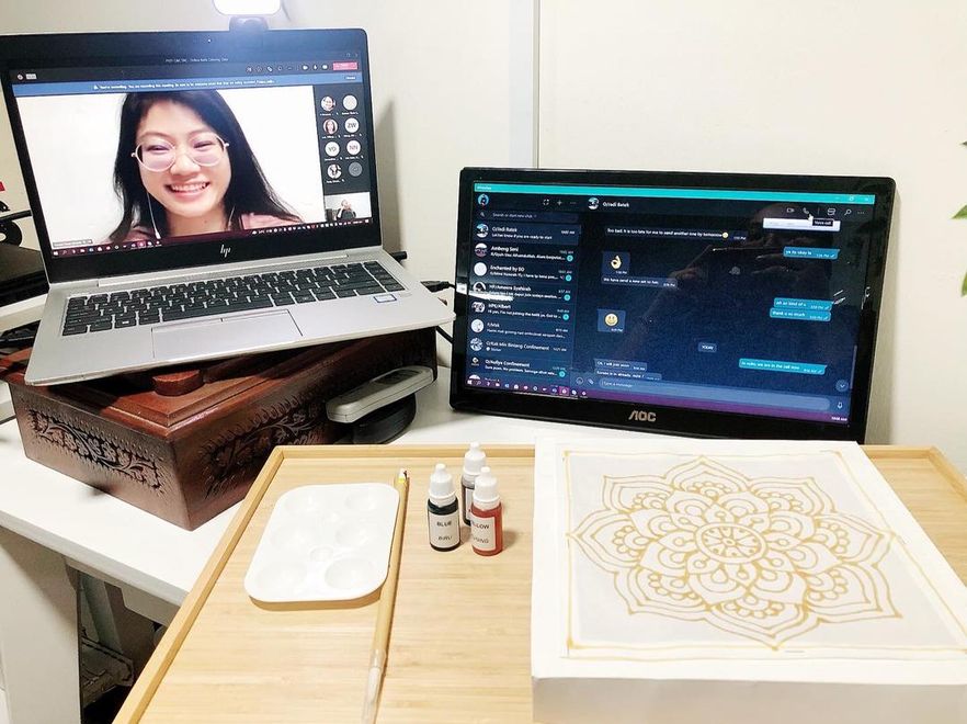 Woman on a video call, alongside materials for a craft project.