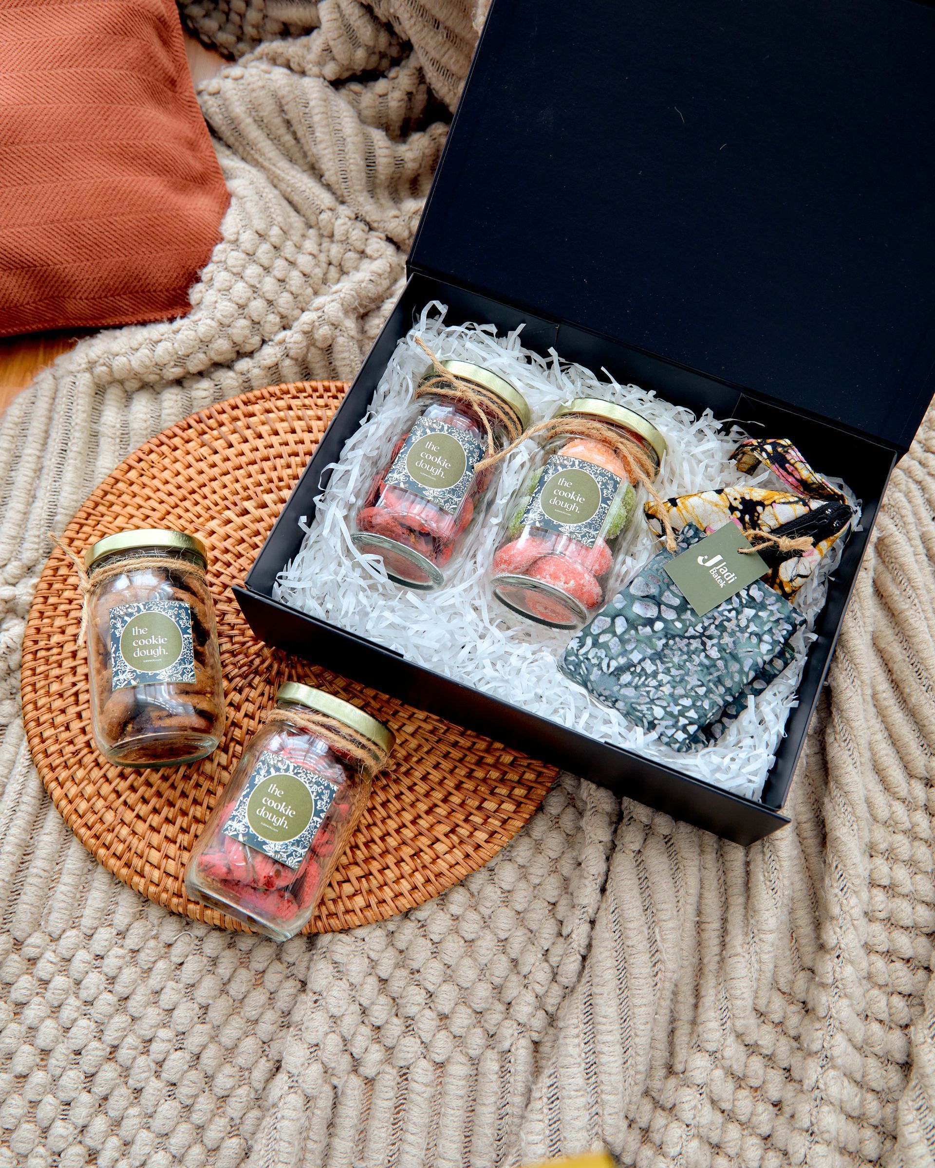 Traditional Malaysian kuih raya gift set featuring assorted festive cookies in glass bottles, paired with handmade batik accessories and premium gift box packaging.