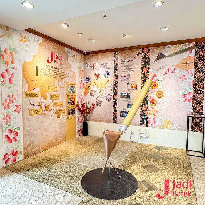 A batik museum display with a large brush sculpture, map and floral patterns.