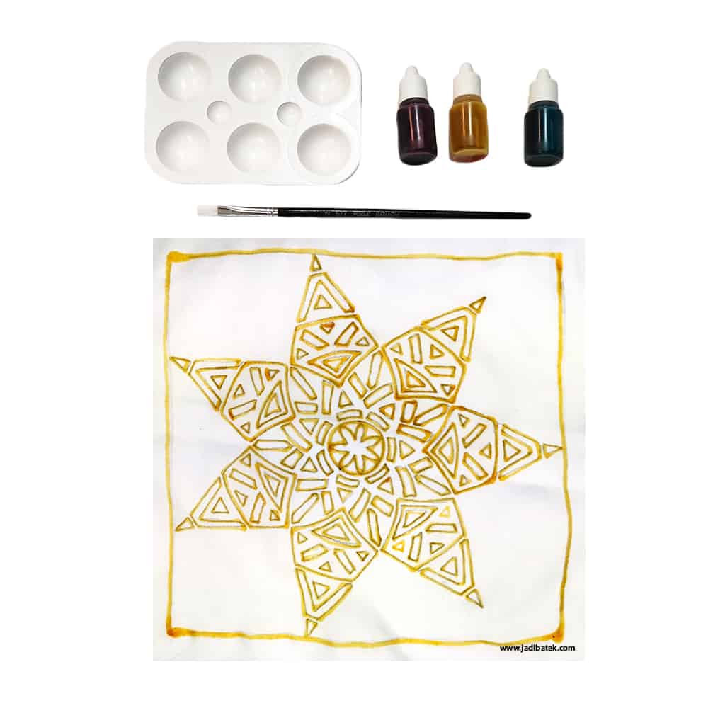 Batik painting kit with paint bottles, palette, brush, and a finished star design on white fabric.