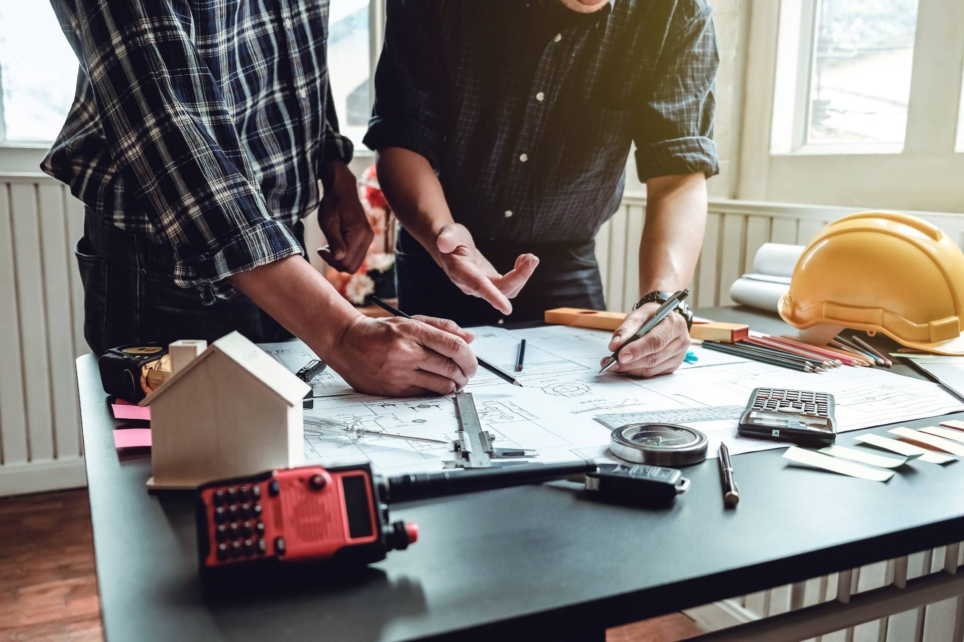 Two men are looking at a blueprint on a table.
