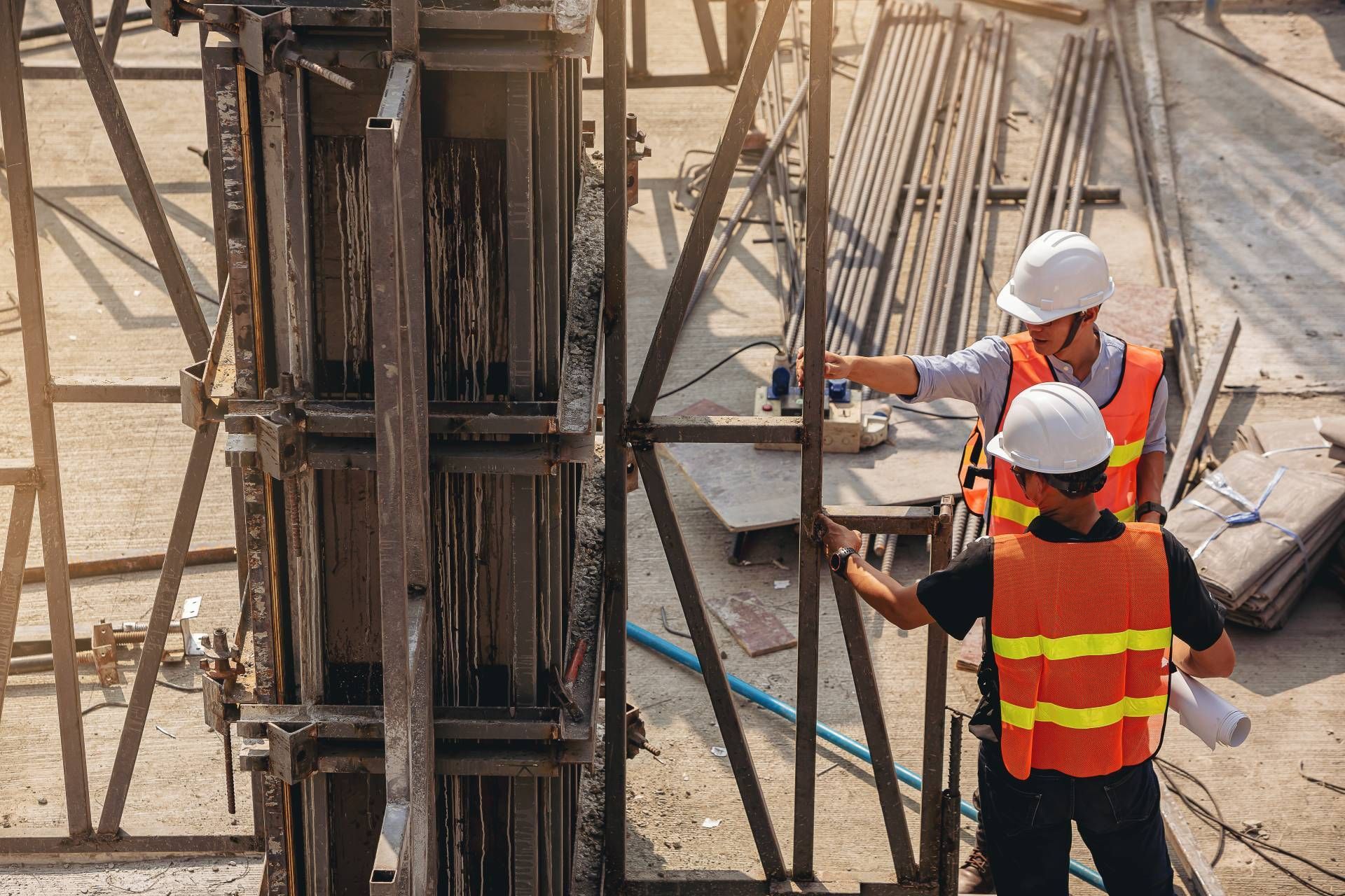 Two construction workers are standing next to each other on a construction site.