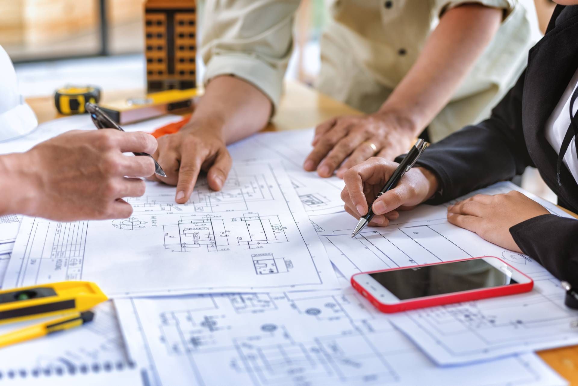 A group of people are sitting around a table looking at a blueprint.