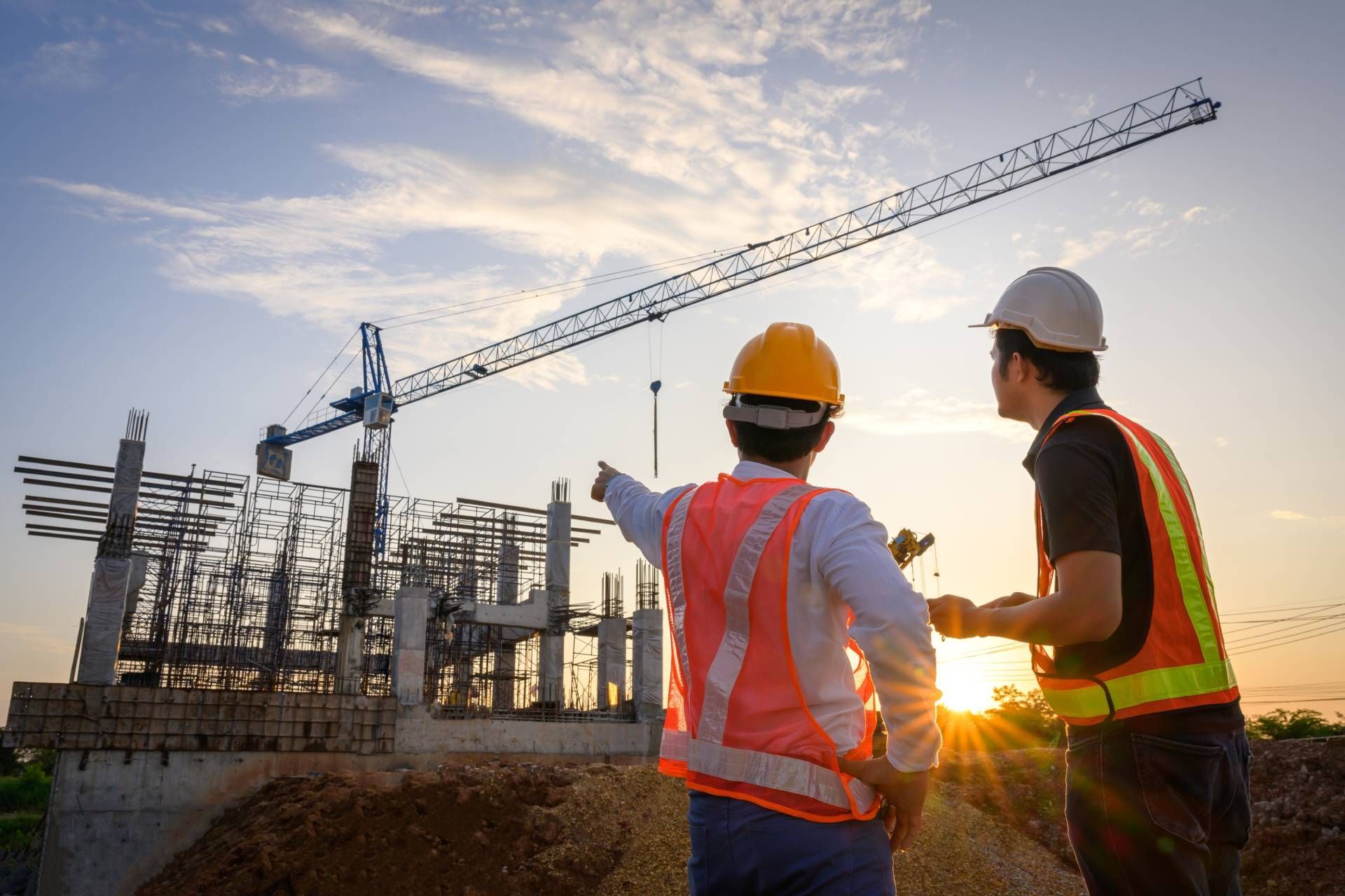 Two construction workers are looking at a building under construction.