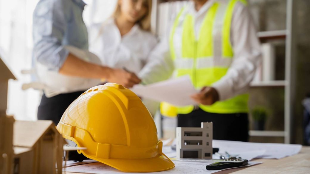 A yellow hard hat is sitting on a table next to a group of construction workers.