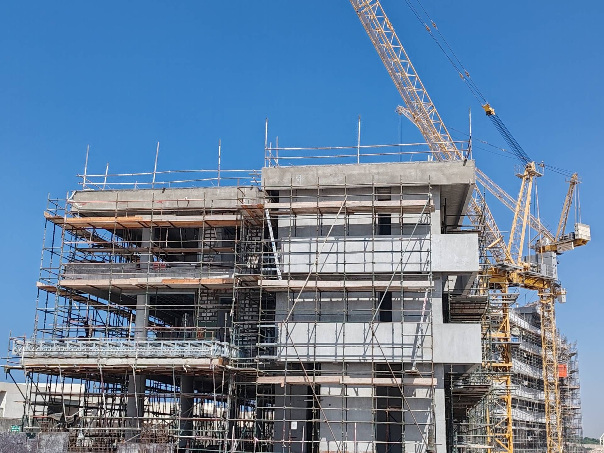 A large building is being built with scaffolding and a crane.