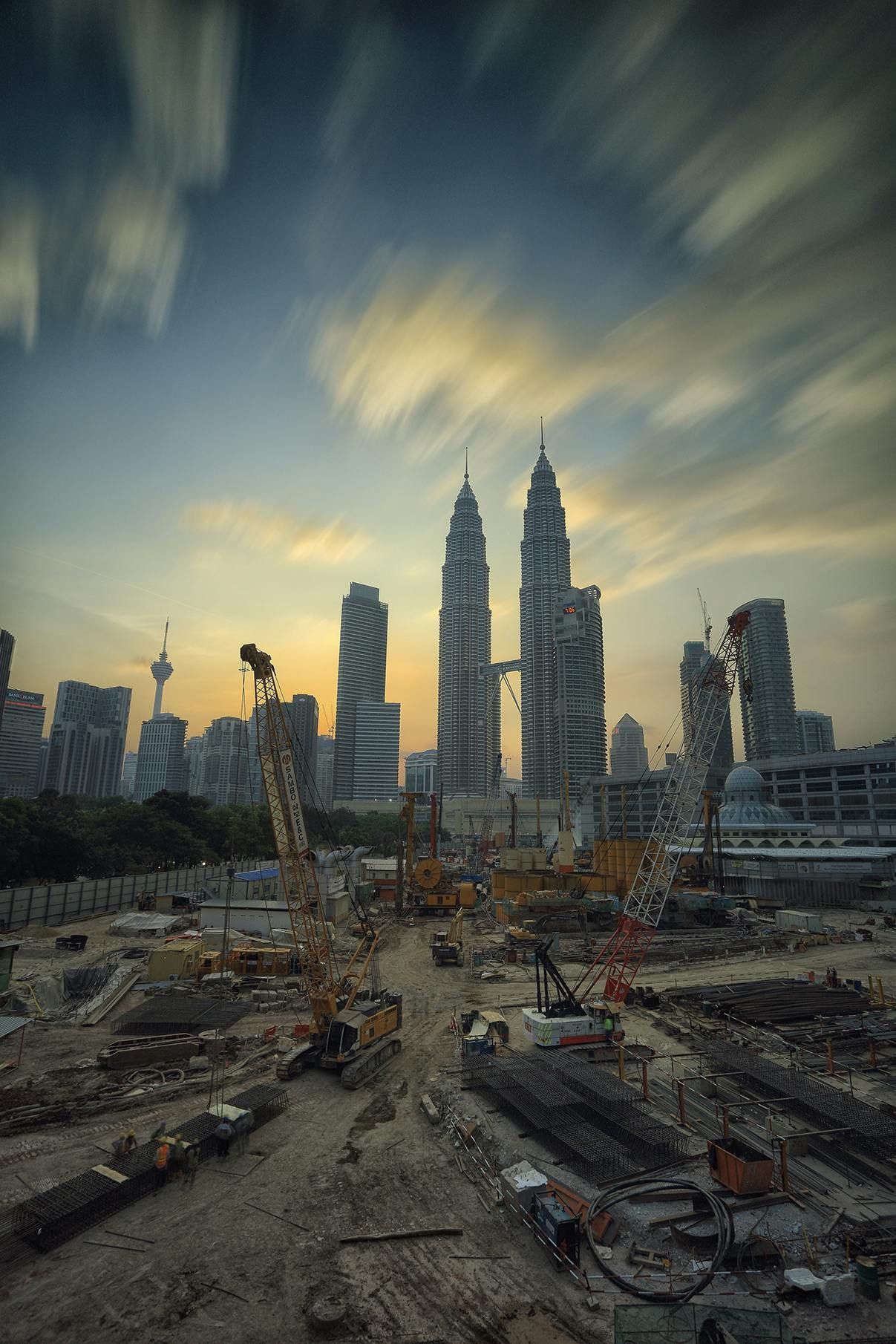 A construction site with a city skyline in the background at sunset.
