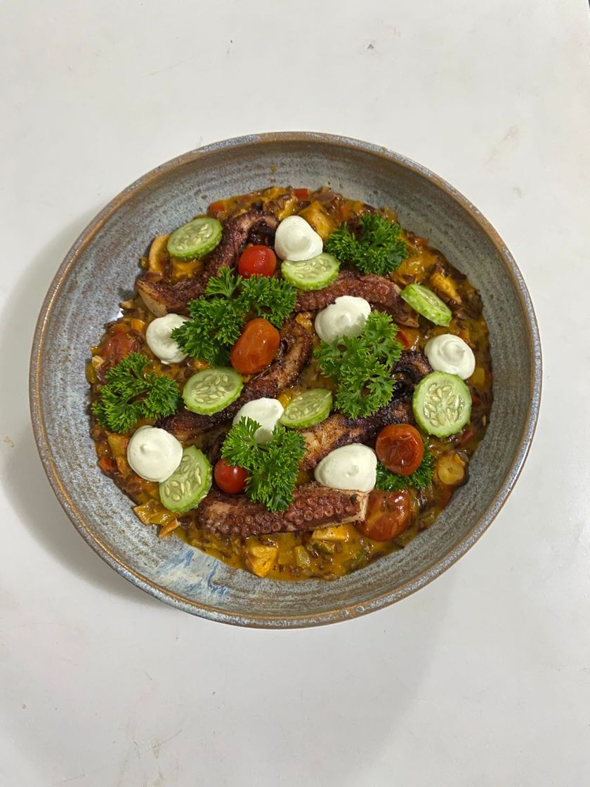 Uma tigela de comida com tomates, pepinos, mussarela e salsa sobre uma mesa.