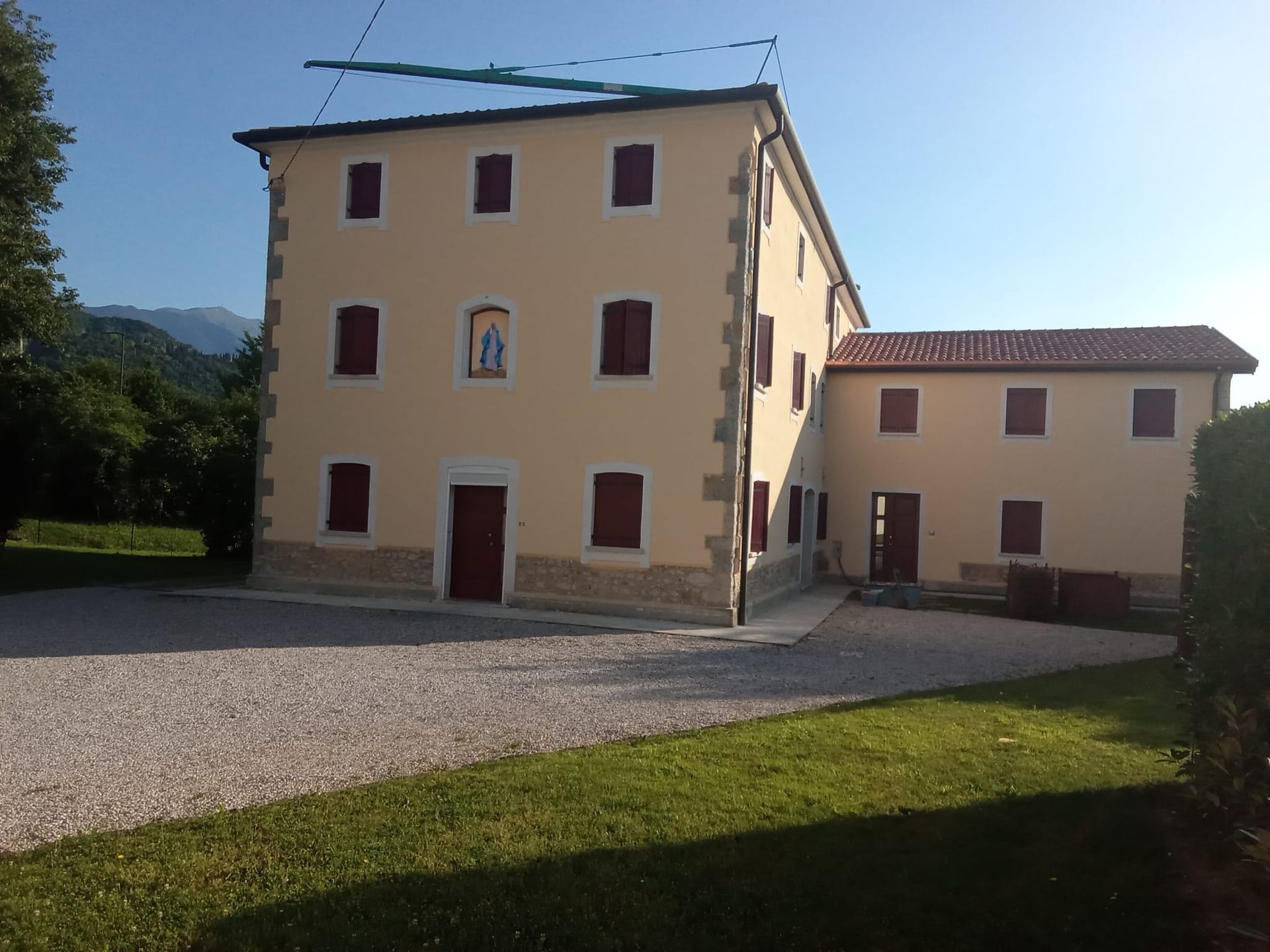 Casa rosa pallido con persiane marroni e cortile di ghiaia sotto un cielo limpido