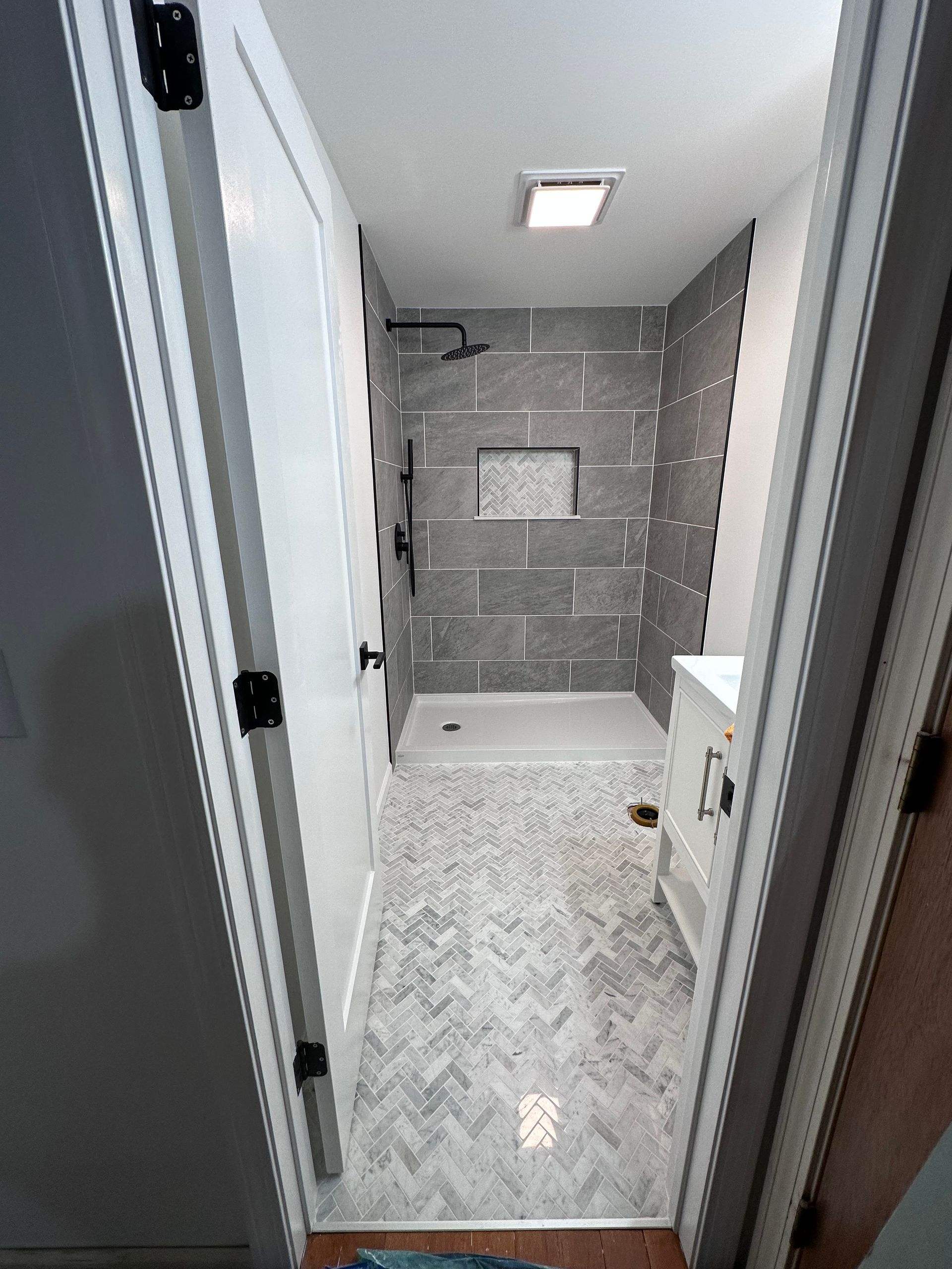 A bathroom with a walk in shower and a sink.