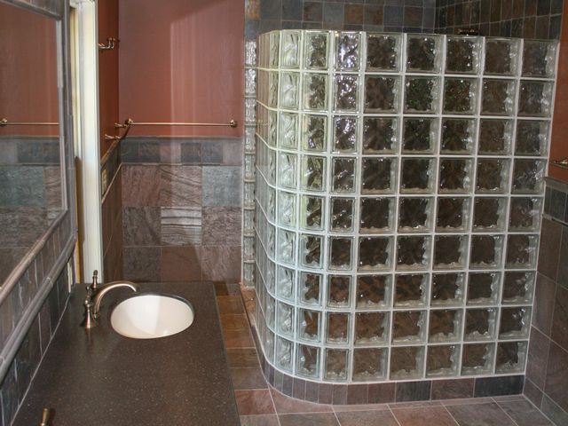 A bathroom with a glass block shower and a sink