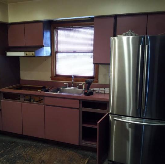 A kitchen with pink cabinets and a stainless steel refrigerator