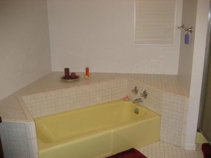 A bathroom with a yellow bathtub in the corner.