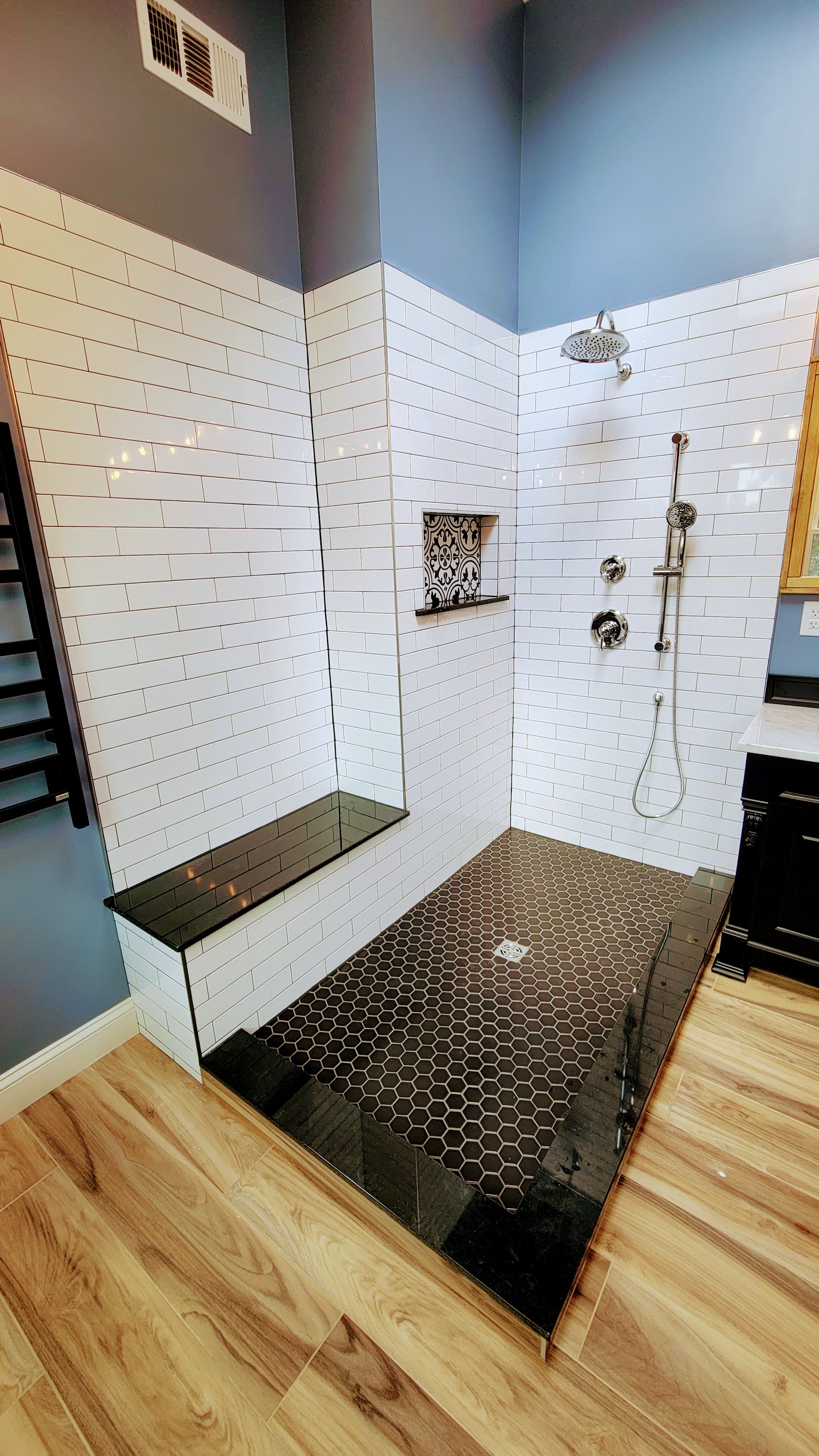 A bathroom with a walk in shower and a black tile floor.