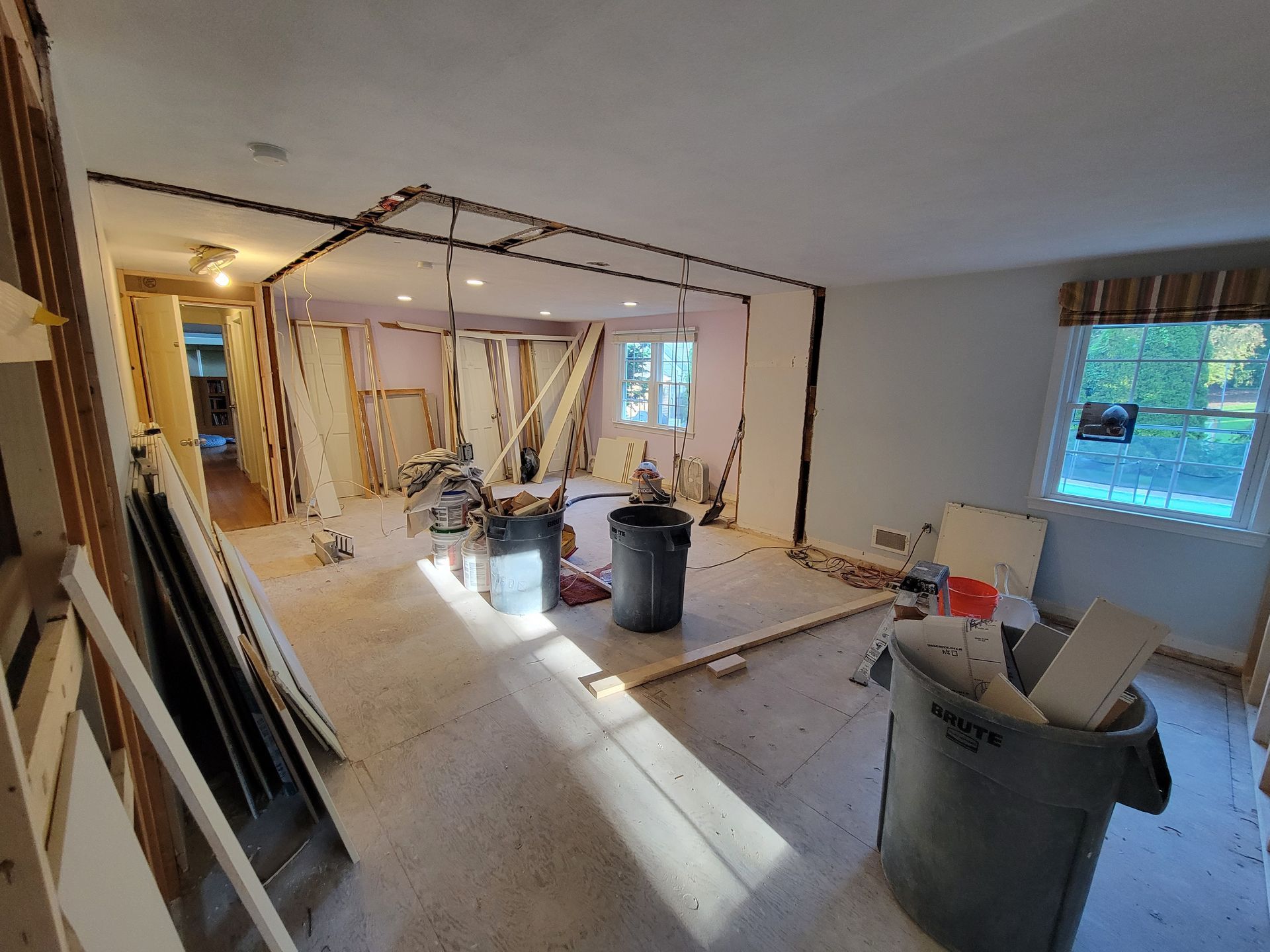 A room under construction with a trash can in the middle of it.