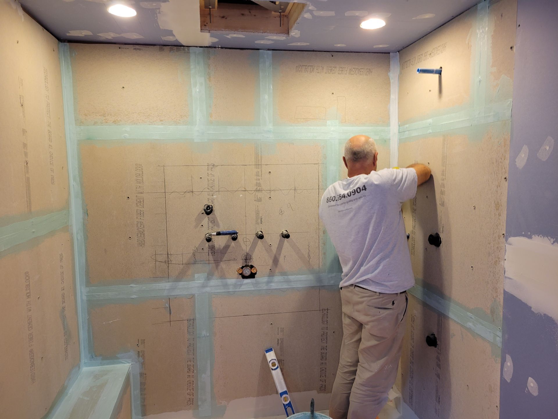 A man is working on a wall in a bathroom.