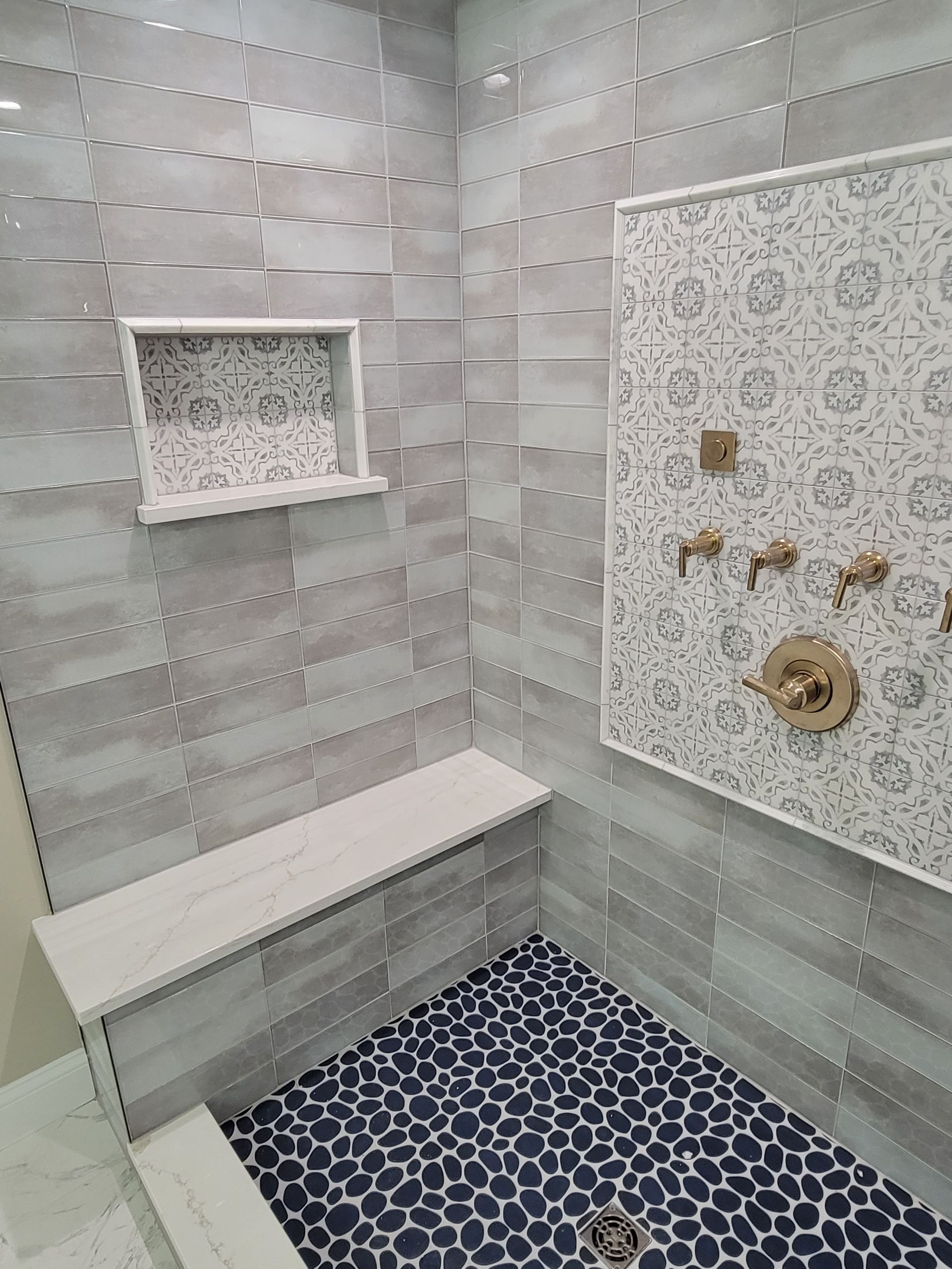 A bathroom with a walk in shower and a bench.