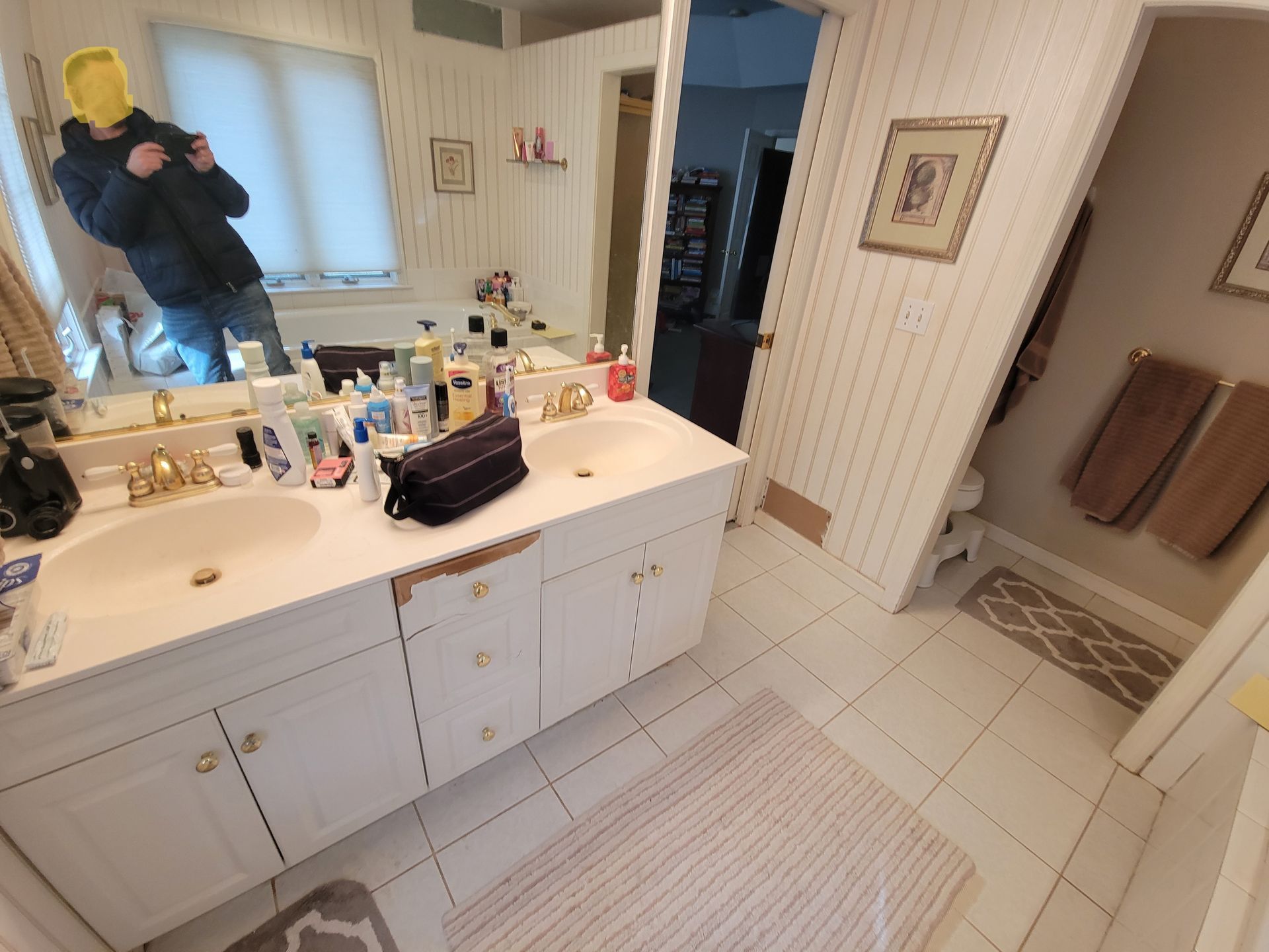 A bathroom with a sink and a mirror and a man taking a picture of himself in the mirror.