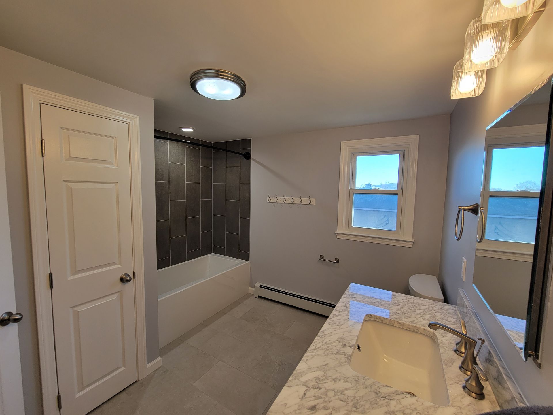 A bathroom with a sink , toilet , tub and mirror.