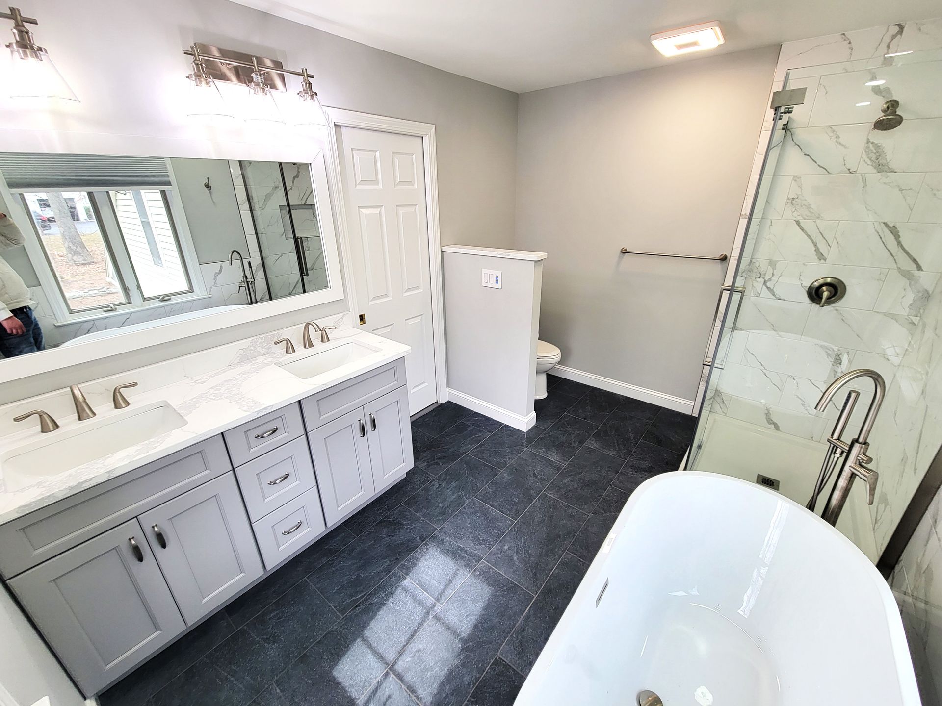 A bathroom with two sinks , a tub , a shower and a mirror.