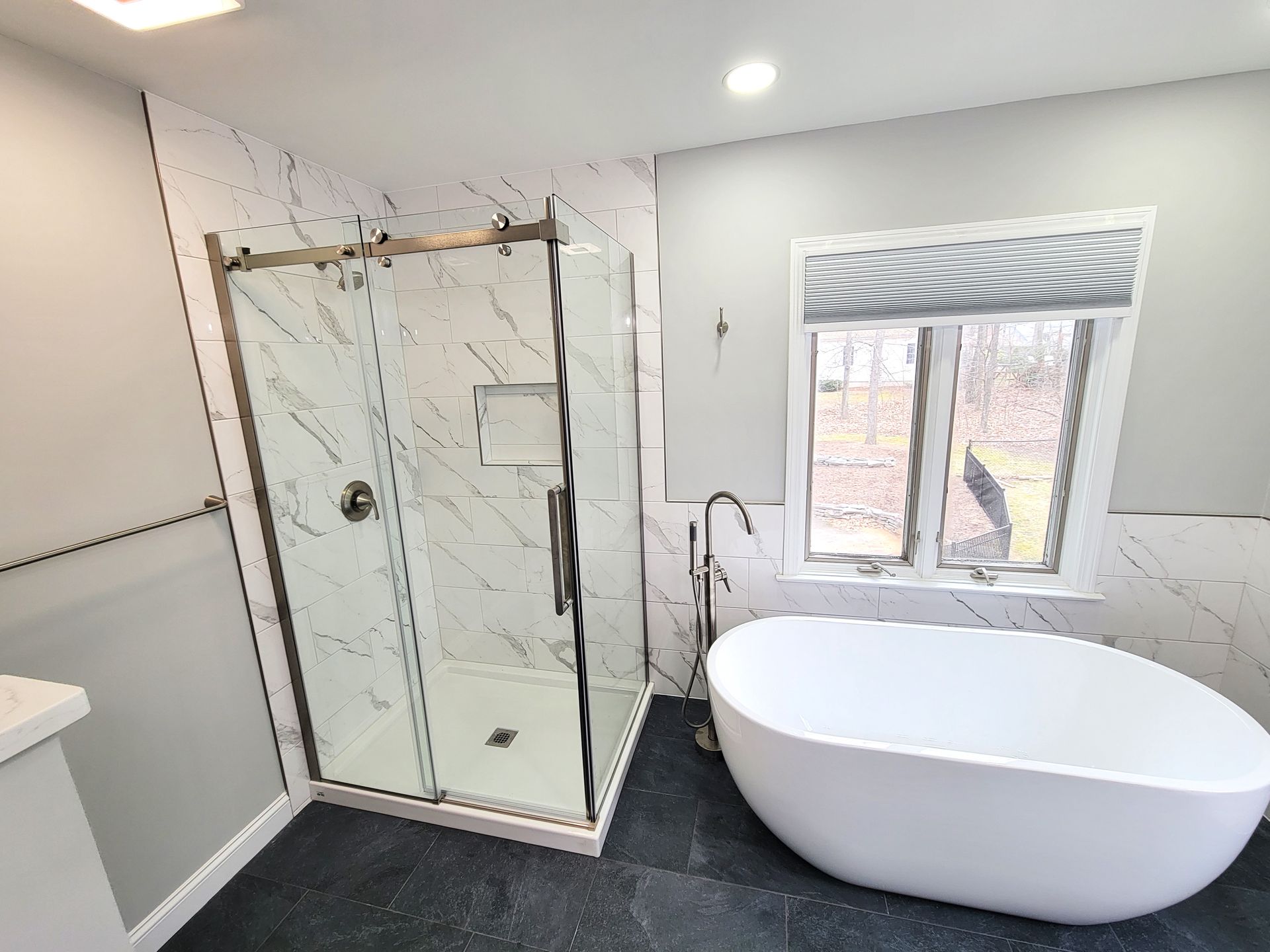 A bathroom with a tub , shower , and window.