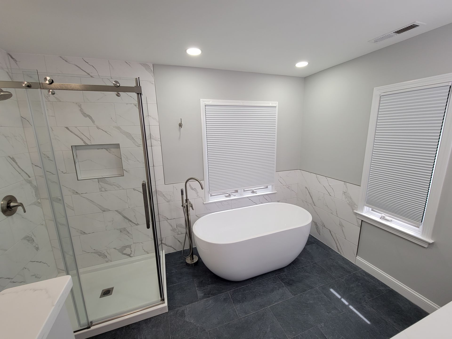 A bathroom with a tub , shower , and window.