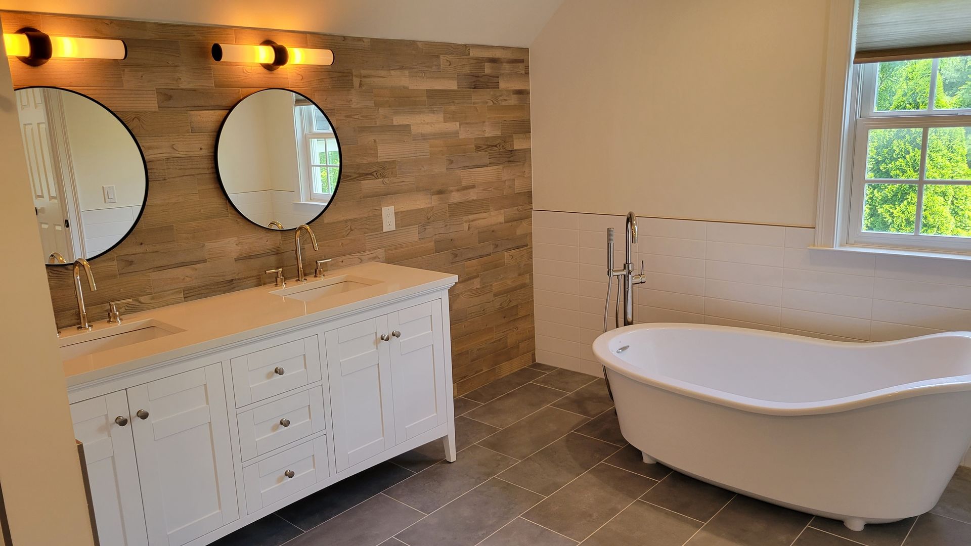 A bathroom with a tub , sinks , mirrors and a window.