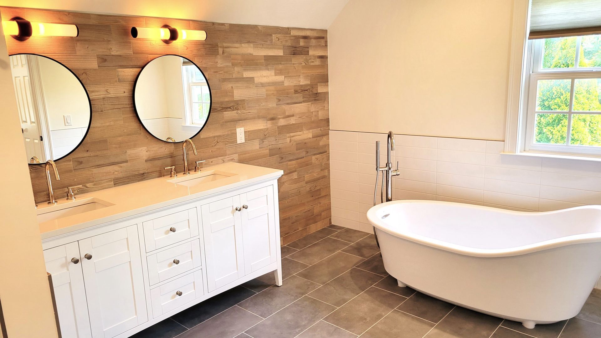 A bathroom with a tub , sinks , mirrors and a window.