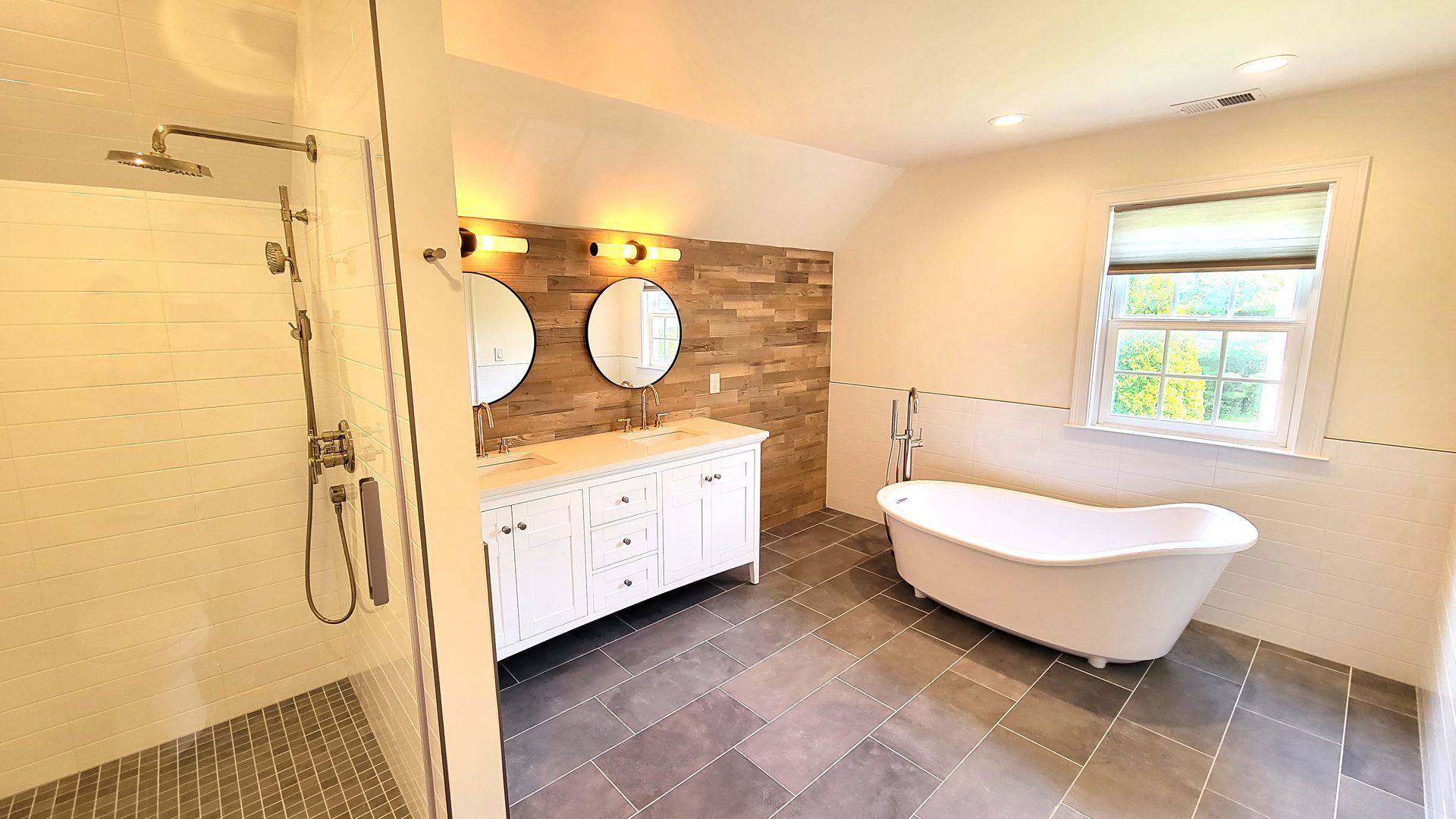 Moder Bathroom in Newington, CTwith white vanity, freestanding tub, and shower, gray tile floor, neutral walls, and window.