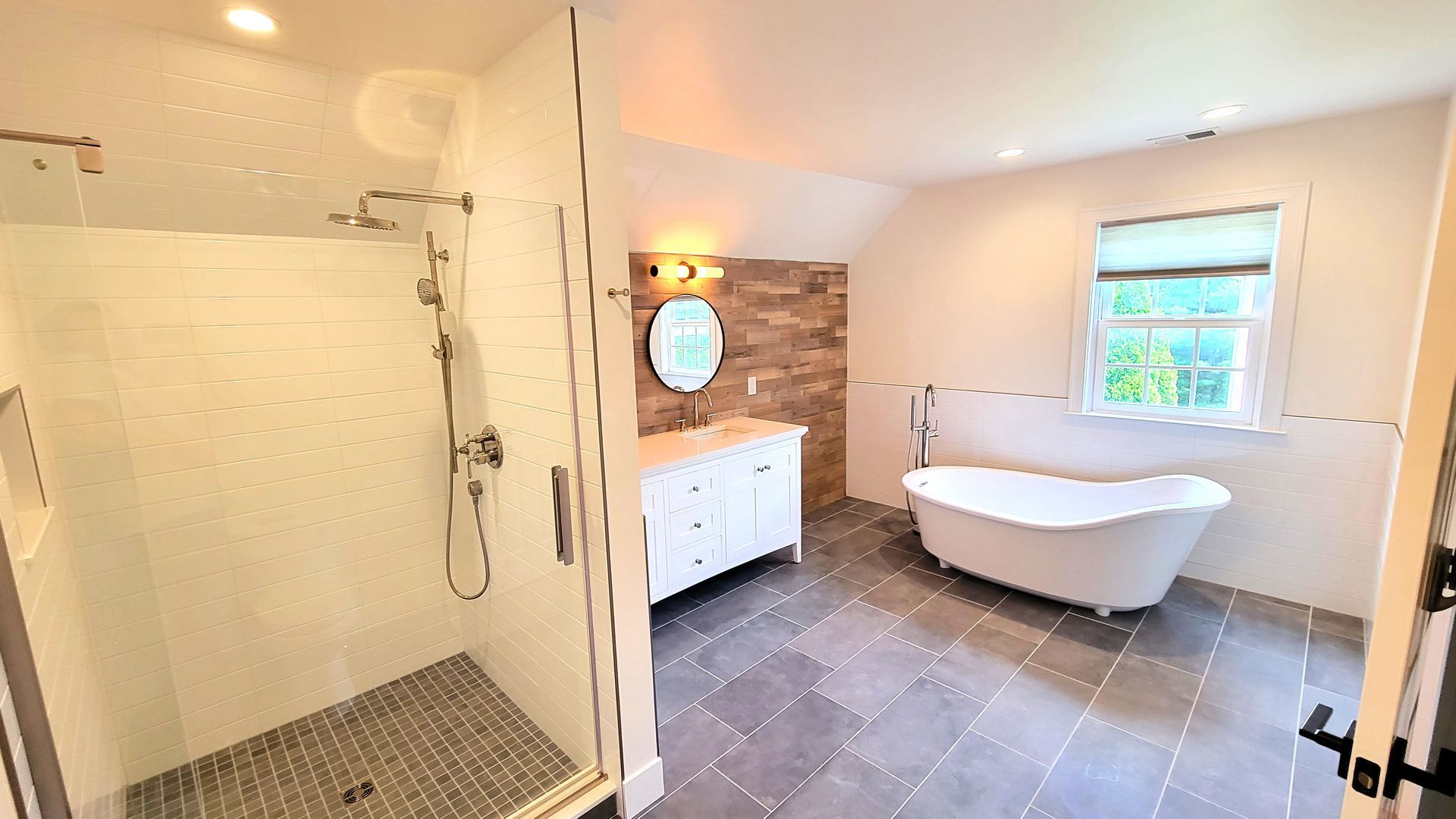 A bathroom with a tub , shower , sink and mirror.