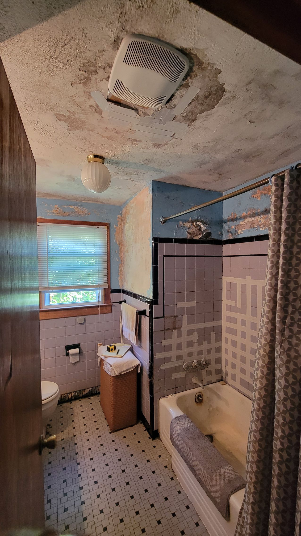 Bathroom with water damage on the ceiling and walls, a toilet, sink, and bathtub.