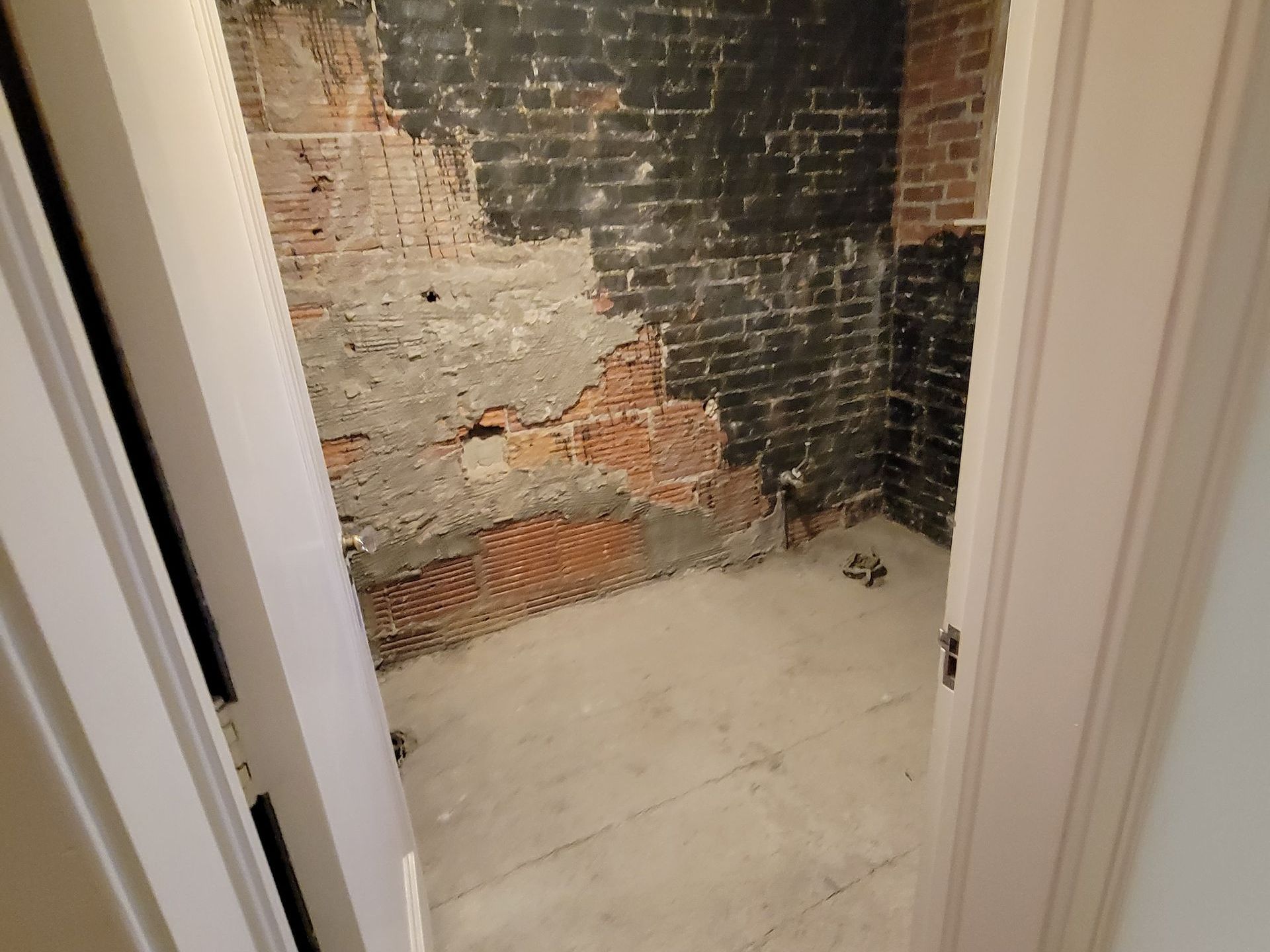 An empty room with a brick wall and a white door.