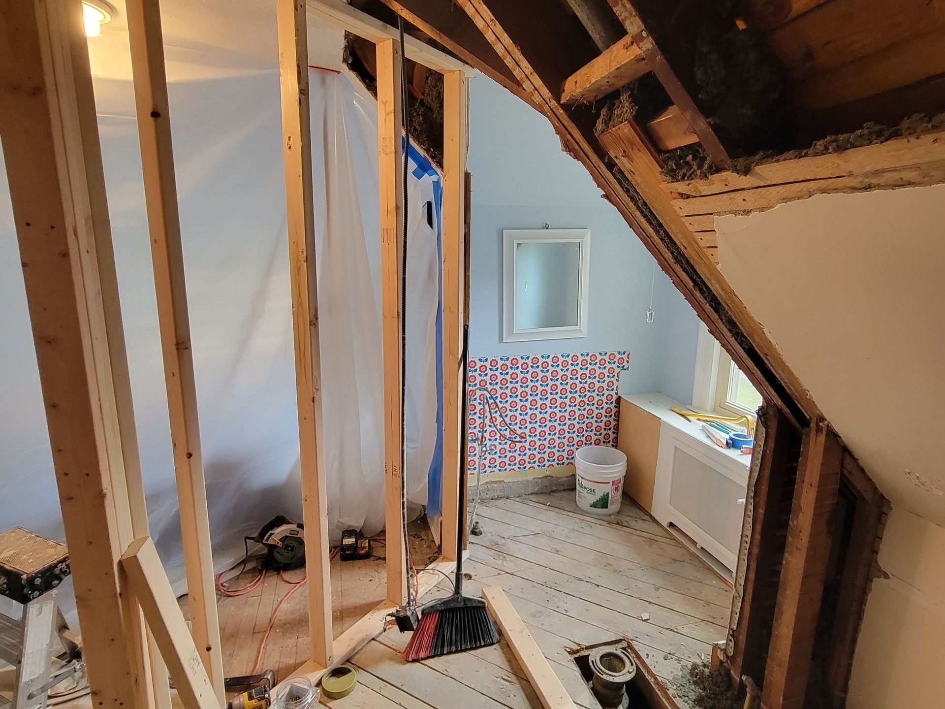A bathroom under construction with wooden beams and a mirror.
